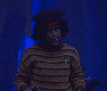 a person in a yellow and black striped sweater is standing in a dark room