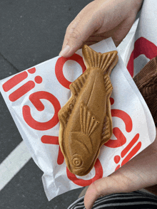 a person is holding a fish shaped pastry on a paper that says go