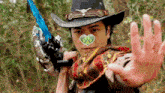 a man in a cowboy hat is holding a sword and a heart on his face .