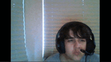 a young man wearing headphones and a microphone makes a funny face