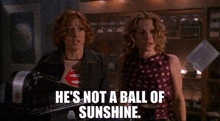 two women standing next to each other with the words `` he 's not a ball of sunshine '' written on the bottom .