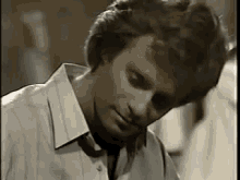 a man in a white shirt and tie is sitting down with his head down and his eyes closed .