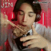a man wearing headphones is eating noodles with chopsticks and the name jin is on the bottom