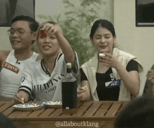 a group of people sitting at a table with a woman wearing a shirt that says filipina on it
