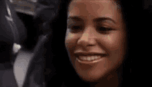 a woman with curly hair is smiling with her hand on her chin