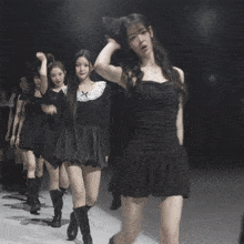 a group of women in black dresses and boots are dancing
