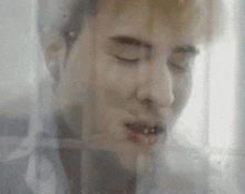 a close up of a man 's face with his eyes closed behind a glass curtain .