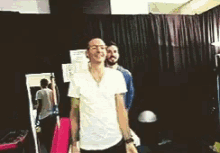 a man in a white shirt is standing next to another man