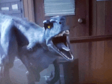 a blue dinosaur with a yellow eye is standing in front of a wooden door