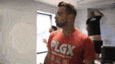 a man wearing a red shirt that says plgs