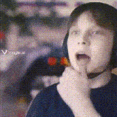 a young boy wearing headphones and a blue shirt is thinking