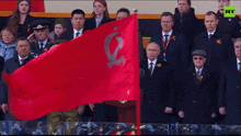 a group of people holding a red flag with the letter e on it