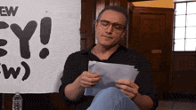 a man sits in front of a sign that says ey