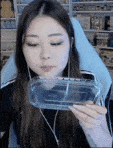 a woman is sitting in a chair holding a clear plastic container with water in it .
