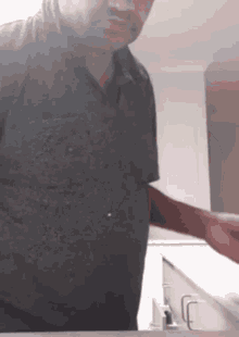 a man in a black shirt is standing in front of a counter
