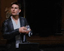 a man in a black leather jacket is holding a piece of paper in his hand .