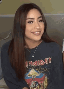 a girl wearing an iron maiden shirt smiles for the camera