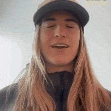 a man with long blonde hair wearing a hat and a jacket