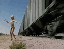 a woman in a bathing suit is walking on train tracks