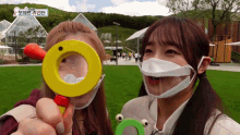 two girls wearing masks are holding a magnifying glass
