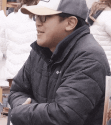 a man wearing a hat and glasses is wearing a black columbia jacket