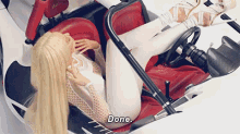 a blonde woman is sitting in a white car and saying done