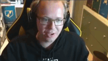 a man wearing glasses and headphones is sitting in a chair and talking on a video call .