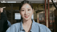 a woman wearing a blue denim jacket is smiling for the camera