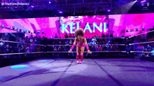 a woman is jumping in a wrestling ring with the name kelani on the screen
