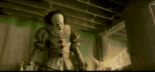 a clown is standing in a dark room holding a sword .