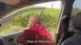 a man in a red cape is driving a car and saying hop on flam blast .