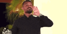 a man with a beard is wearing a black shirt and wrist watch