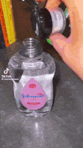 a bottle of johnson 's baby oil is being poured into another bottle