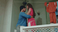 a man and a woman are standing on a balcony looking at each other