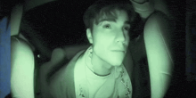 a man is sitting in the back seat of a car with a green light shining on his face .