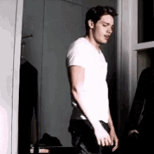 a man in a white shirt is standing in front of a mirror .