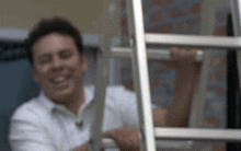 a man in a white shirt is smiling and holding a ladder