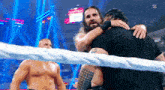 a wrestler is hugging another wrestler in a ring .