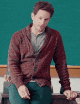 a man in a red sweater sits at a desk