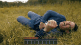 a man in a blue shirt is laying in a field