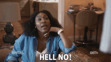 a woman is sitting on a couch and says " hell no "