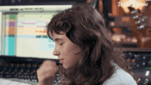 a woman sitting in front of a computer with rolling stone written on the bottom left