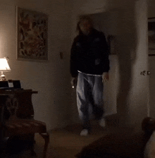 a man in a black jacket is pointing a gun at a woman in a room .