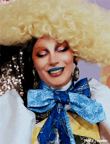 a close up of a drag queen wearing a wig and a blue bow tie