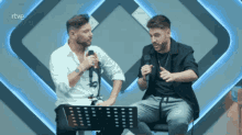 two men are sitting in front of microphones with rtve written on the bottom of the screen