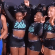 a group of cheerleaders are posing for a picture and one of them is wearing a crop top that says elite .