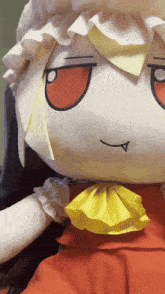 a close up of a stuffed doll with a yellow bow around her neck
