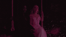 two women are sitting on a swing in a dark room