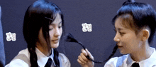 two girls are playing with each other 's hair and one of them is holding a braid .