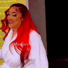 a woman with red hair is wearing a white robe that says adore